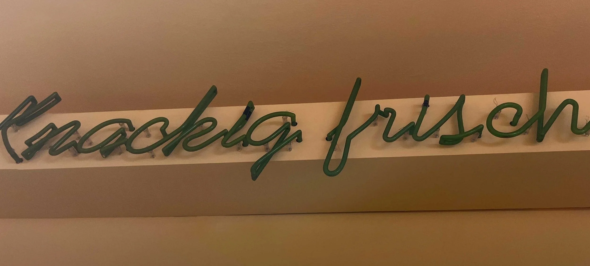 Grüner Neon-Schriftzug an der Wand, der das Wort 'harmony' schreibt.