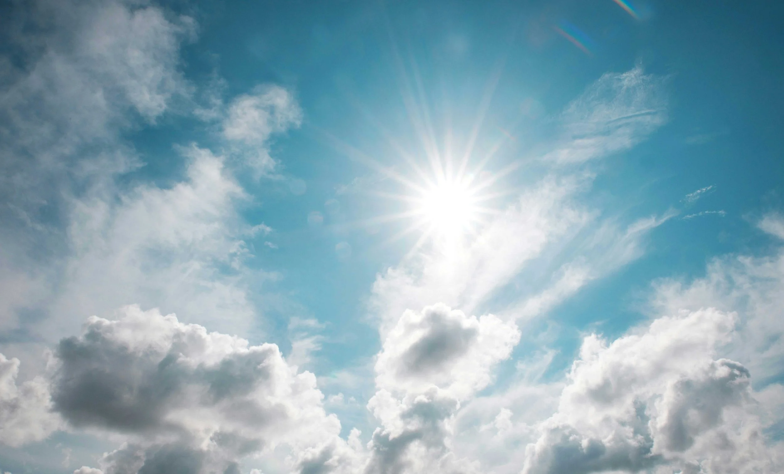 Der Himmel mit Sonnenstrahlen, Wolken und blauer Atmosphäre.