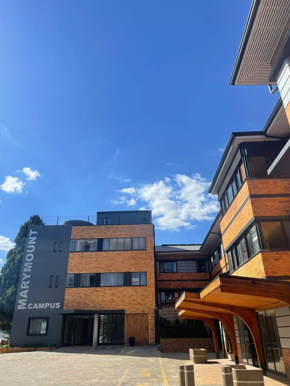 Photo of Marymount campus building with brick and dark gray exterior, large windows, and a clear blue sky overhead.