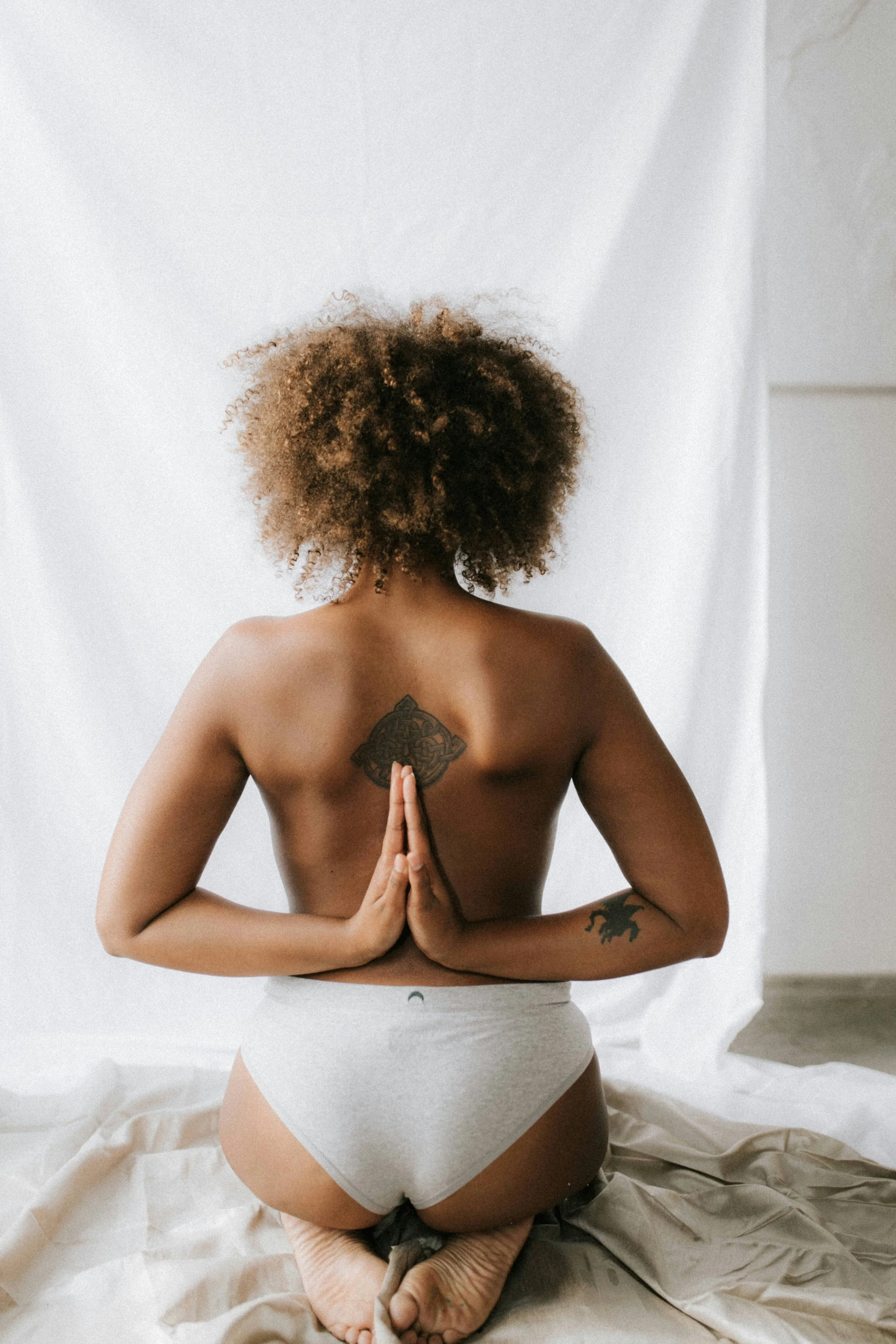 Woman in a reflective seated pose with hands clasped behind her back representing women's health and inner strength