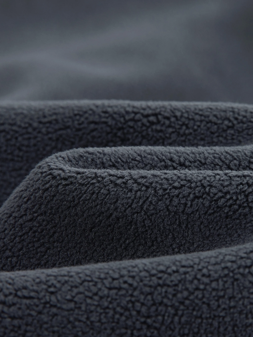 Close-up of dark gray, textured fleece fabric with folds.