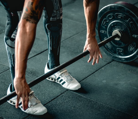 Person preparing to lift a barbell during a workout.
