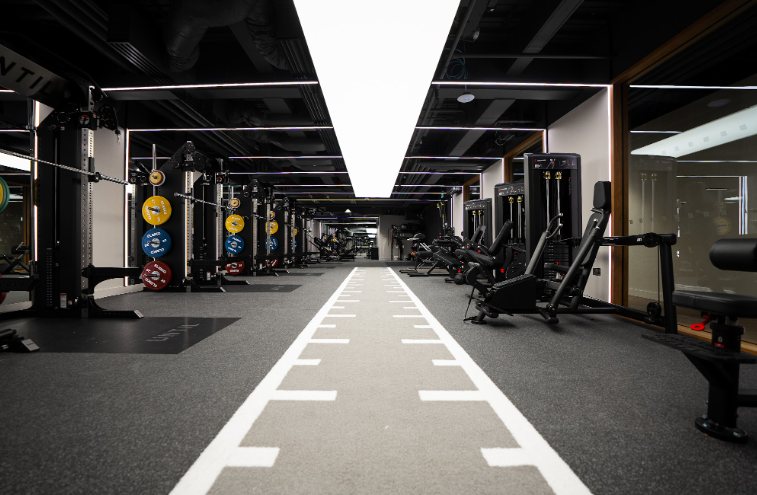 Empty indoor gym with workout equipment and a running track in the center.