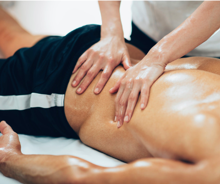 Someone giving a massage to a person's back, focusing on the lower back area.