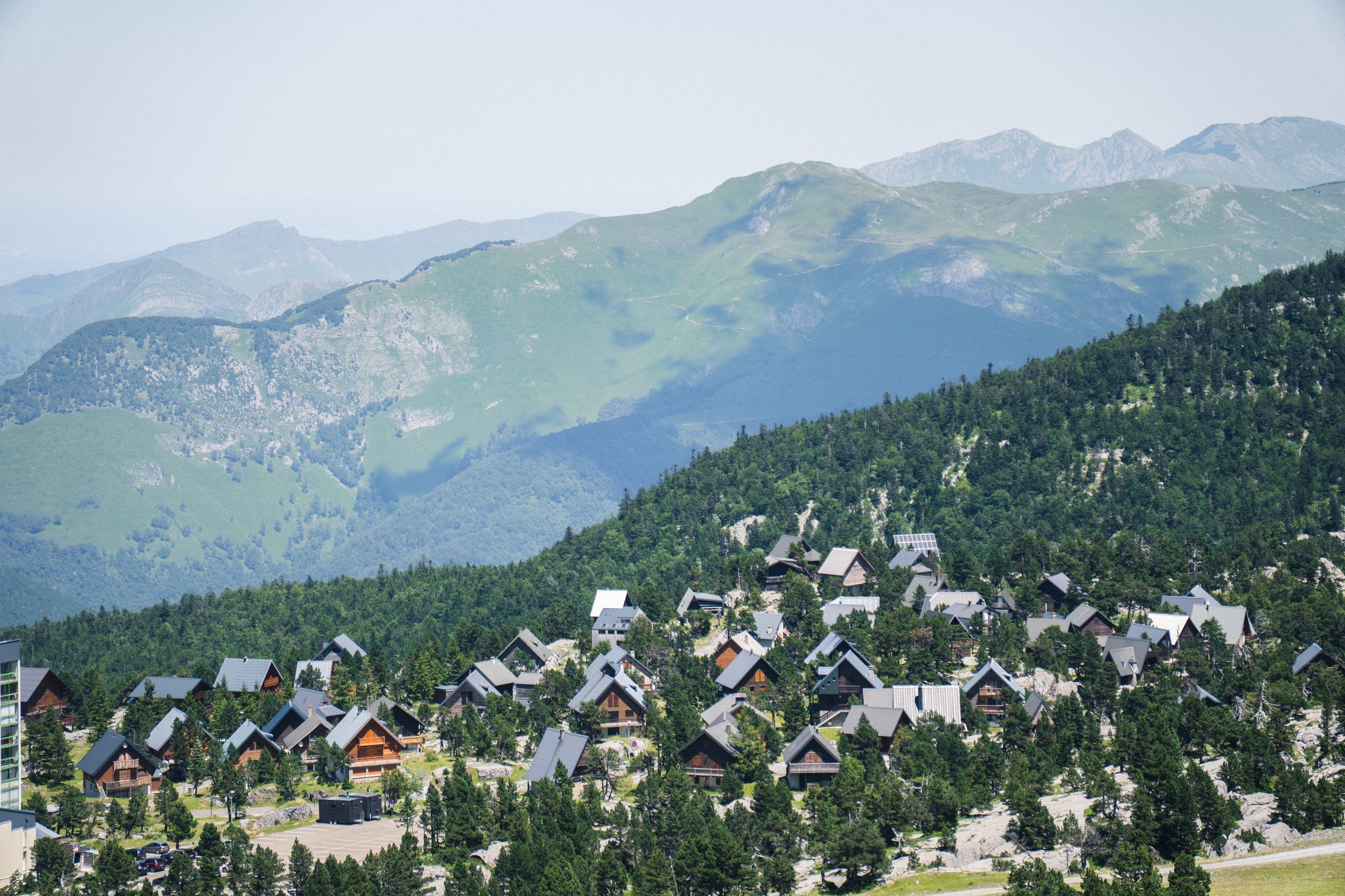Vue de montagnes verdoyantes avec un petit village de maisons en folie sur la pente d'une colline, ciel clair.