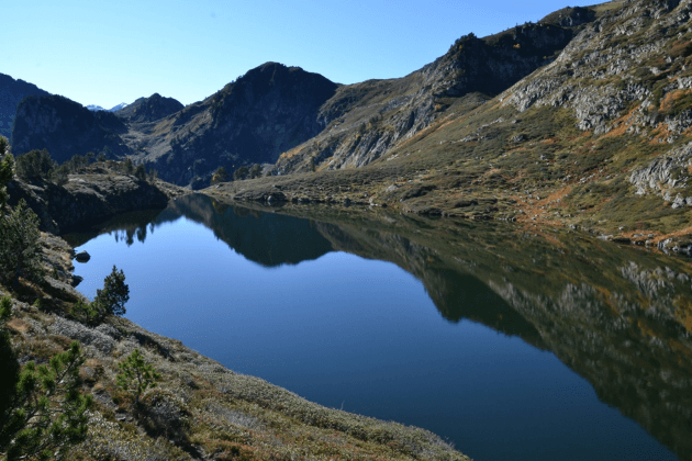 Un lac de montagne entouré de collines rocheuses sous un ciel clair