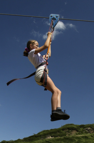 Jeune fille faisant de la tyrolienne dans un ciel bleu.