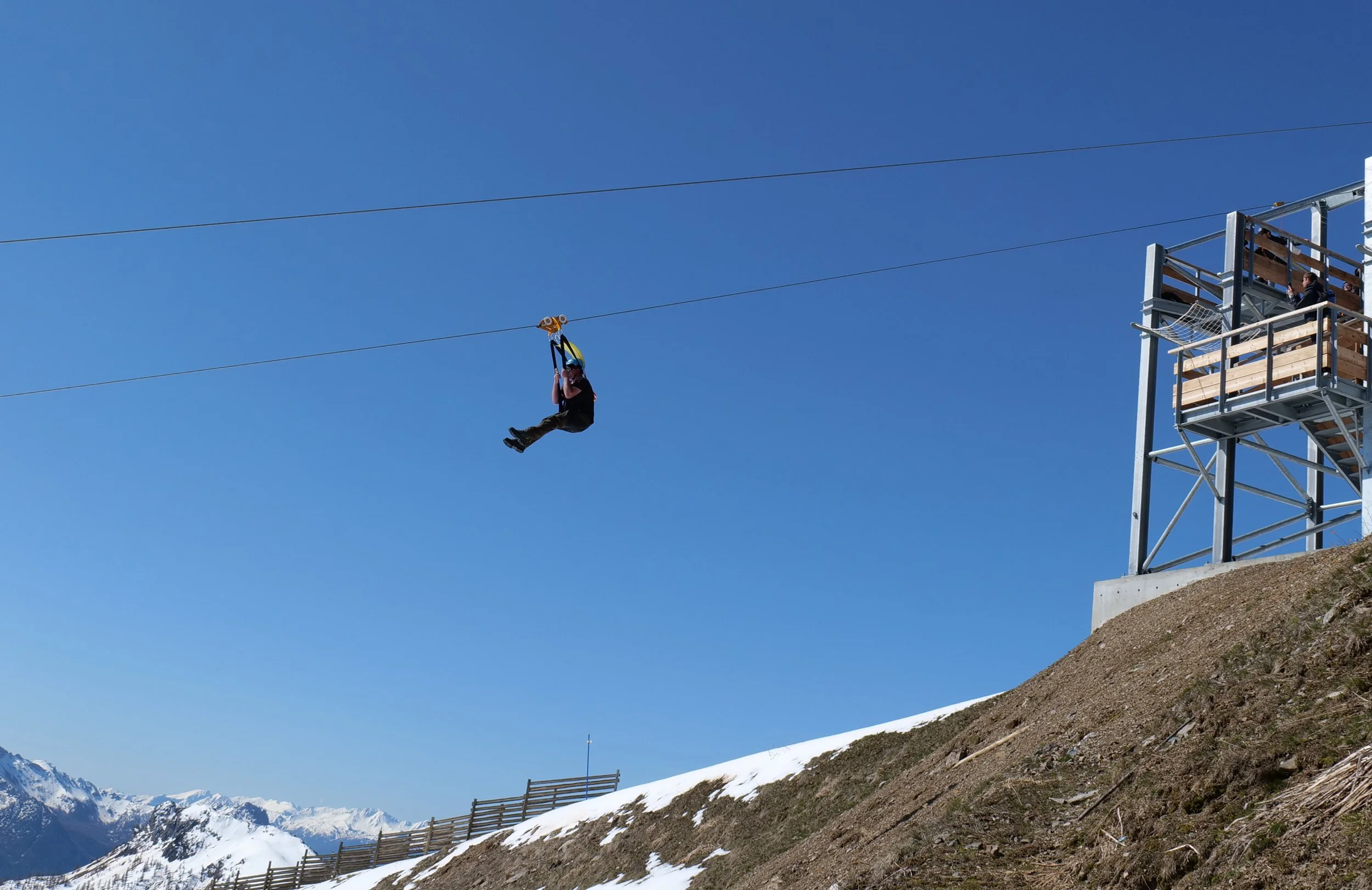 Une personne faisant du ski dans une forêt enneigée avec des arbres recouverts de neige, sous un ciel partiellement nuageux.