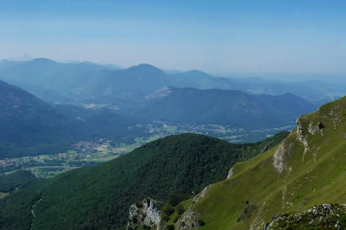 Paysage de montagnes verdoyantes avec des vallées et un ciel bleu clair