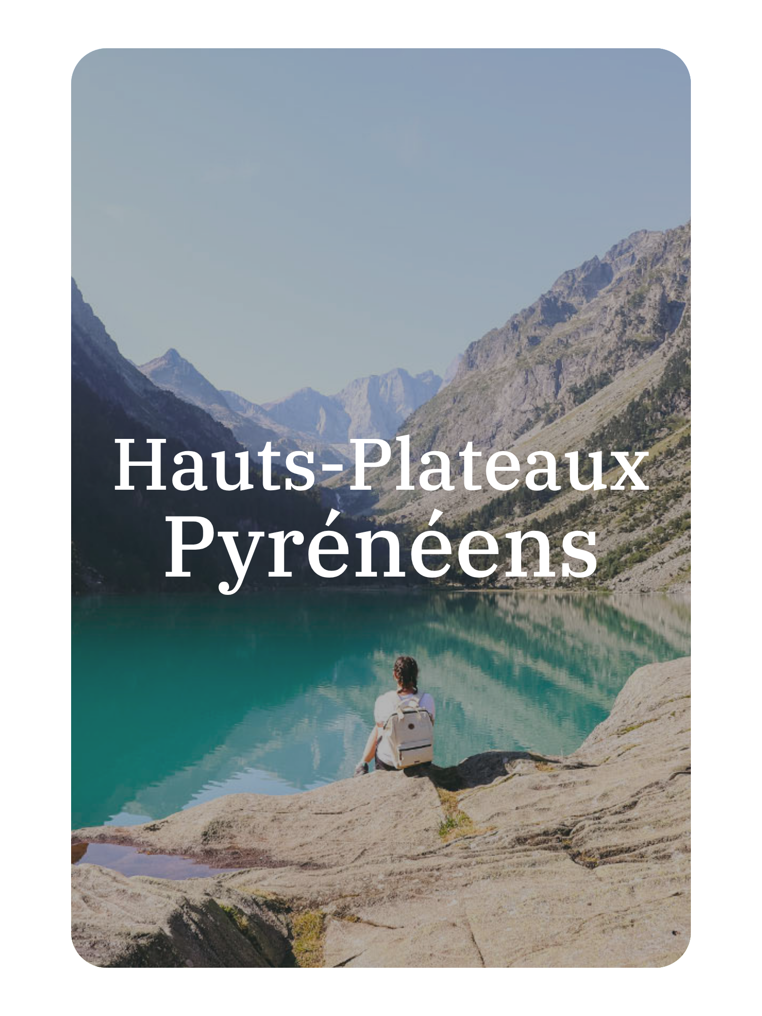 Une personne assise sur un rocher, regardant un lac turquoise entouré de montagnes dans les Pyrénées.