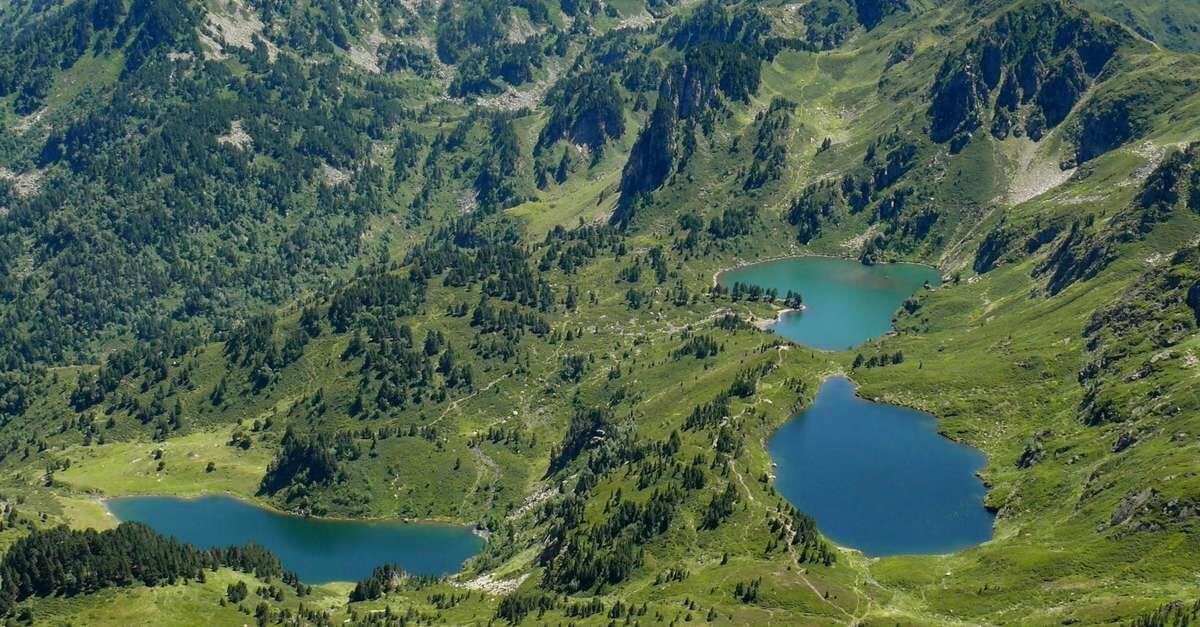 Trois lacs dans une vallée entourée de montagnes verdoyantes et de forêts.