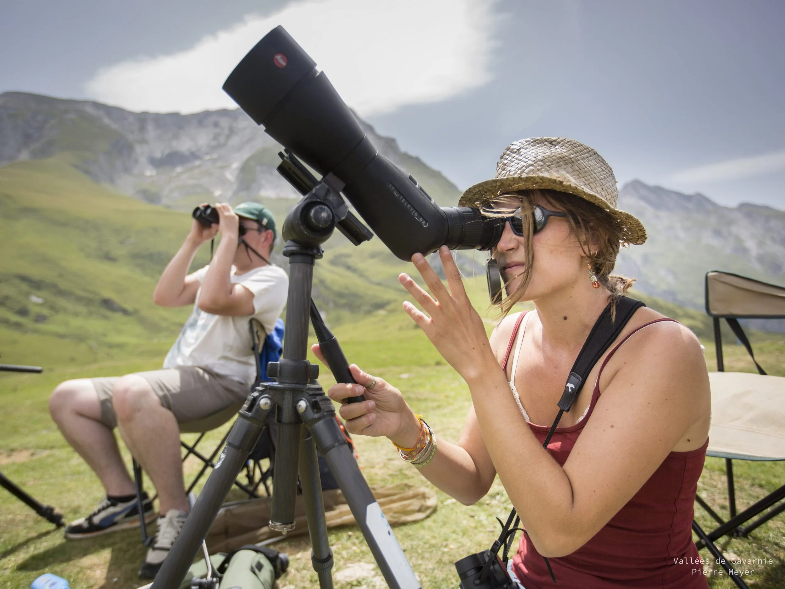 Deux personnes observant le ciel avec des télescopes dans un paysage montagnard en plein air.