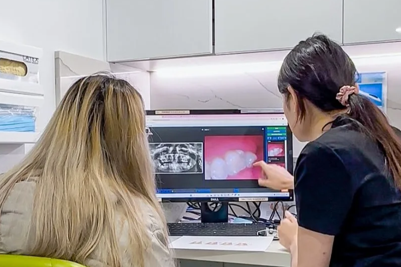 A dentist discussing dental X-rays and close-up of teeth with a patient in a dental office.