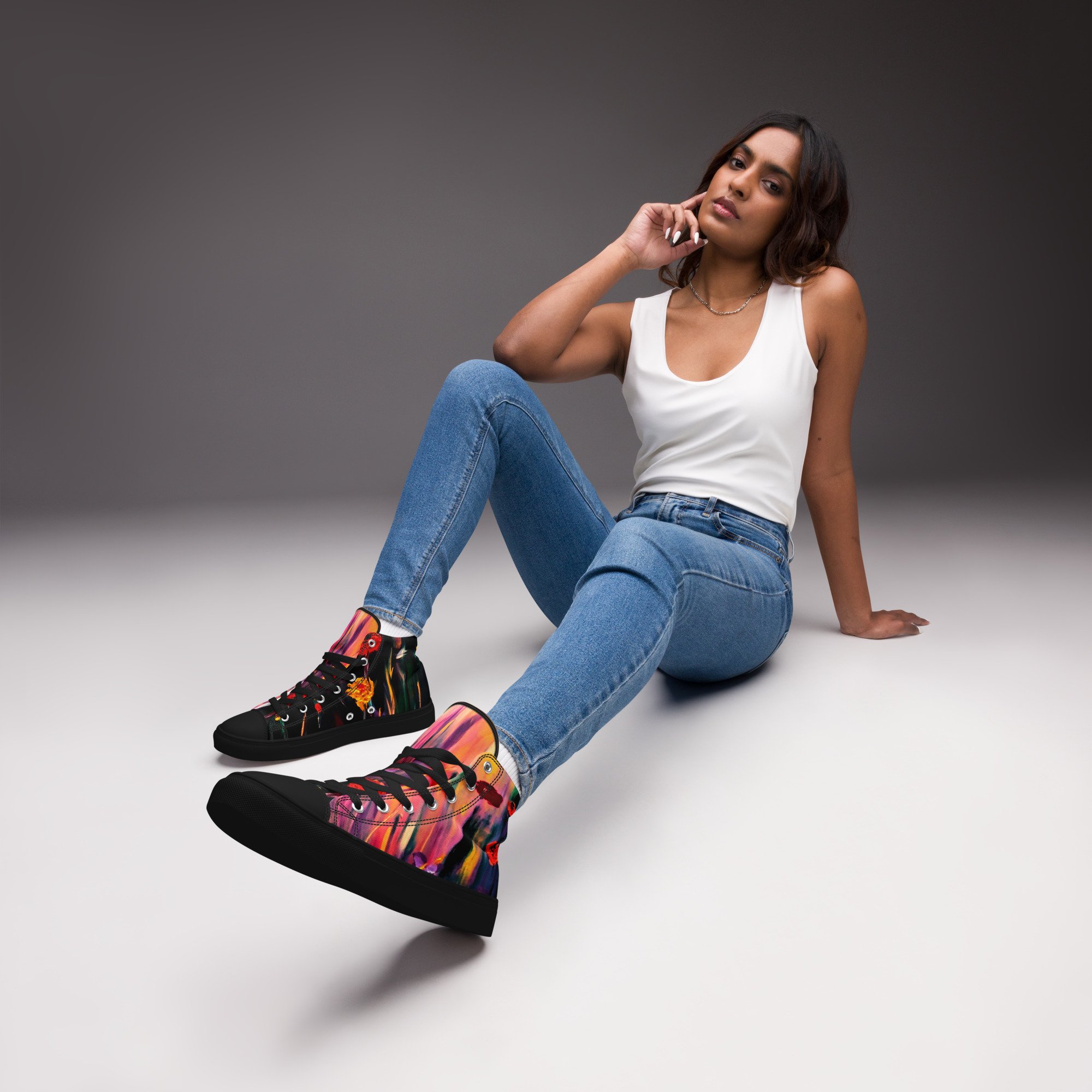 Woman in jeans and white singlet , wearing women’s high-top canvas shoes featuring a vibrant poppy floral print, with bold red flowers and botanical detailing for a colourful, artistic everyday look.