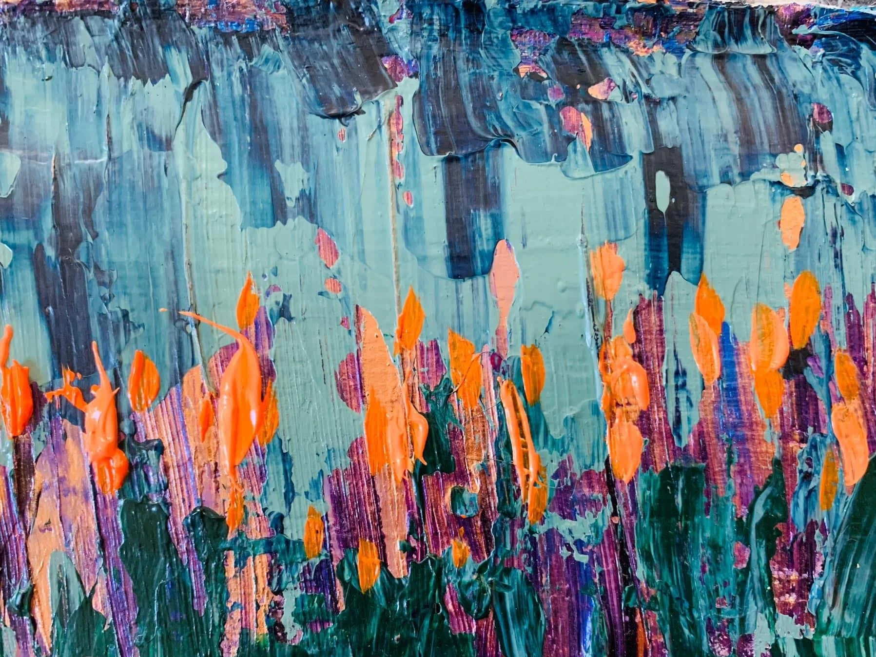 An expressive abstract floral painting featuring vibrant orange blooms emerging through layers of deep green, purple and earthy tones. Thick, textured brushstrokes create a rich, tactile surface, while the cool blue-grey background contrasts dramatic