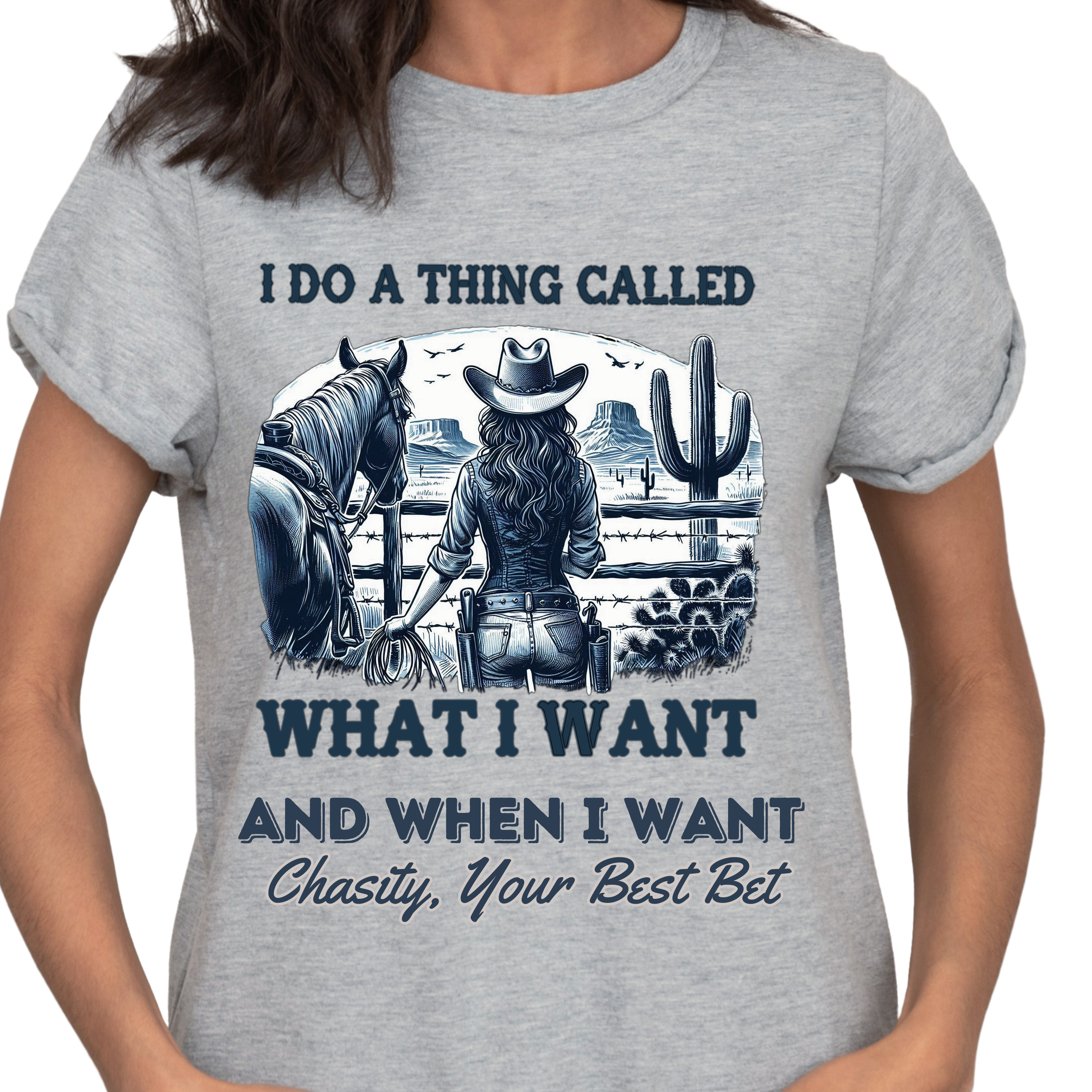Close-up of a person's gray t-shirt with a graphic of a woman in a cowboy hat holding a lasso, standing in front of a desert with cacti and rock formations, and the text 'I DO A THING CALLED WHAT I WANT AND WHEN I WANT'.
