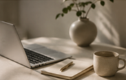 Laptop, notebook, pen, coffee mug, and a vase on a desk