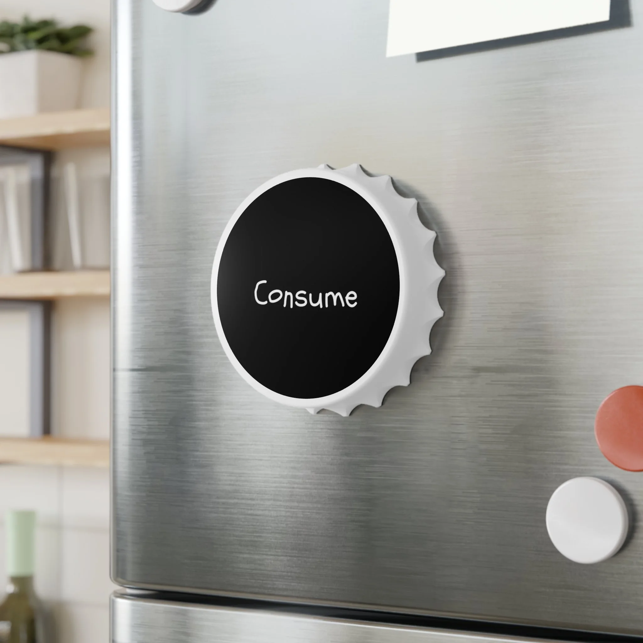Close-up of a stainless steel refrigerator with a kitchen magnet featuring a black circle with the word 'Consume' written on it, and other magnets nearby.
