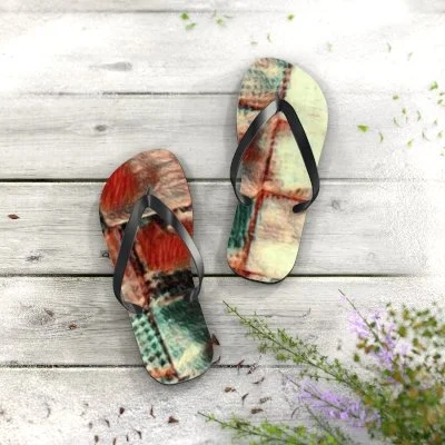 Pair of colorful patterned flip-flops on a wooden surface with purple flowers nearby.