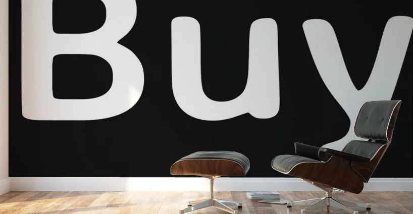Modern lounge chair and ottoman in front of a black wall with large white letters spelling 'Buy'