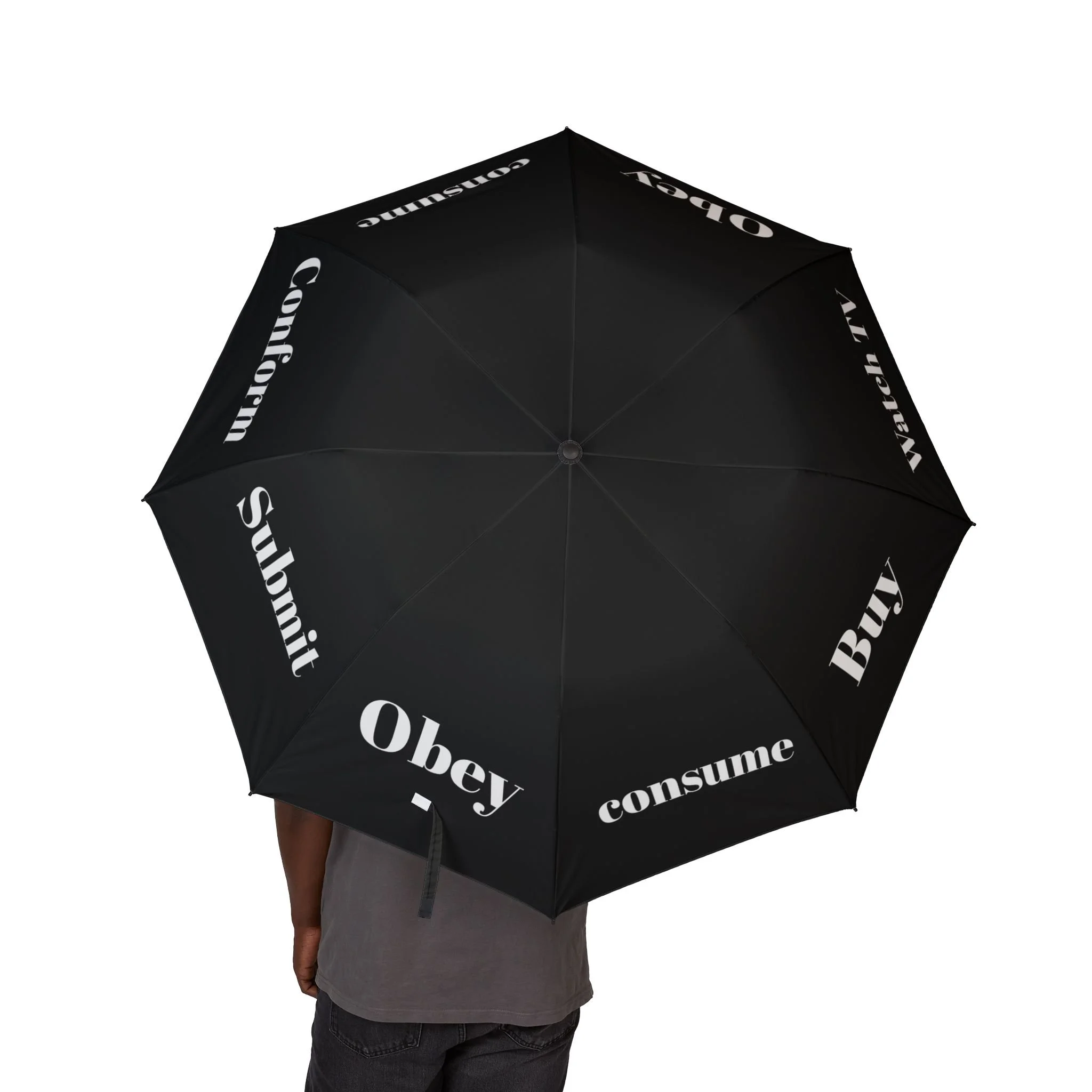 Person holding a large black umbrella with the words 'Obey', 'consume', 'Buy', 'Slap it', 'Confirm', and 'Watch TV' printed on it in white text.