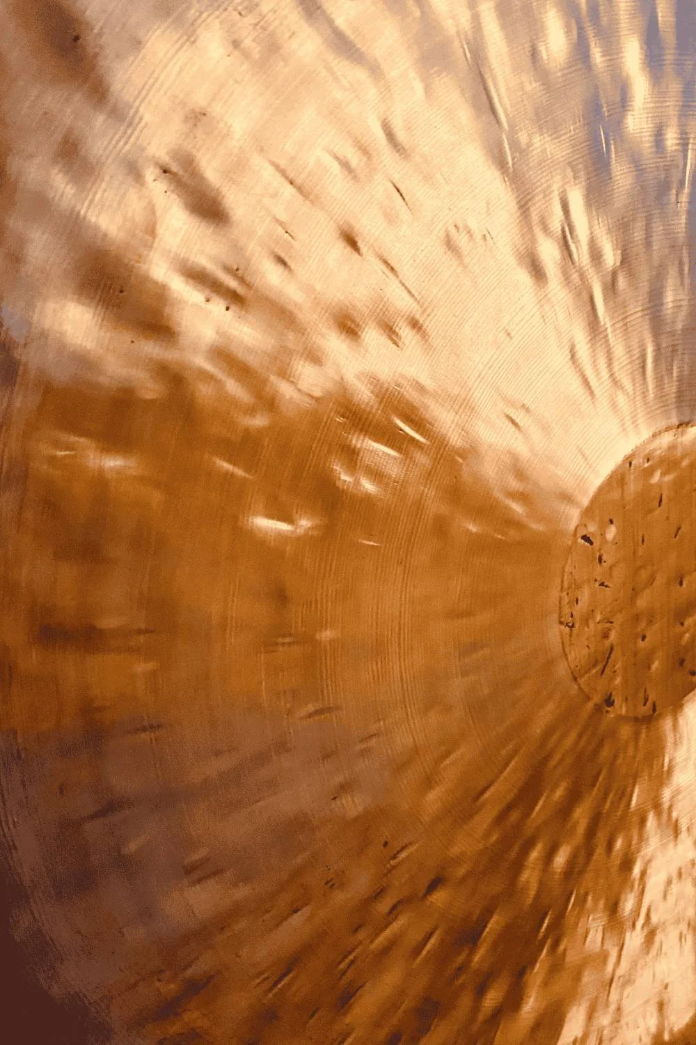 Close-up of the interior surface of a large copper or brass vessel with circular grooves and some marks.