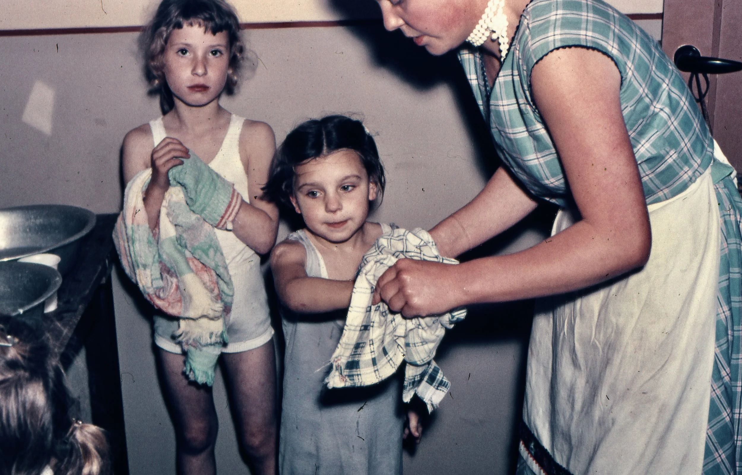 Moeder droogt handen twee meisjes, ca. 1955 [WS]