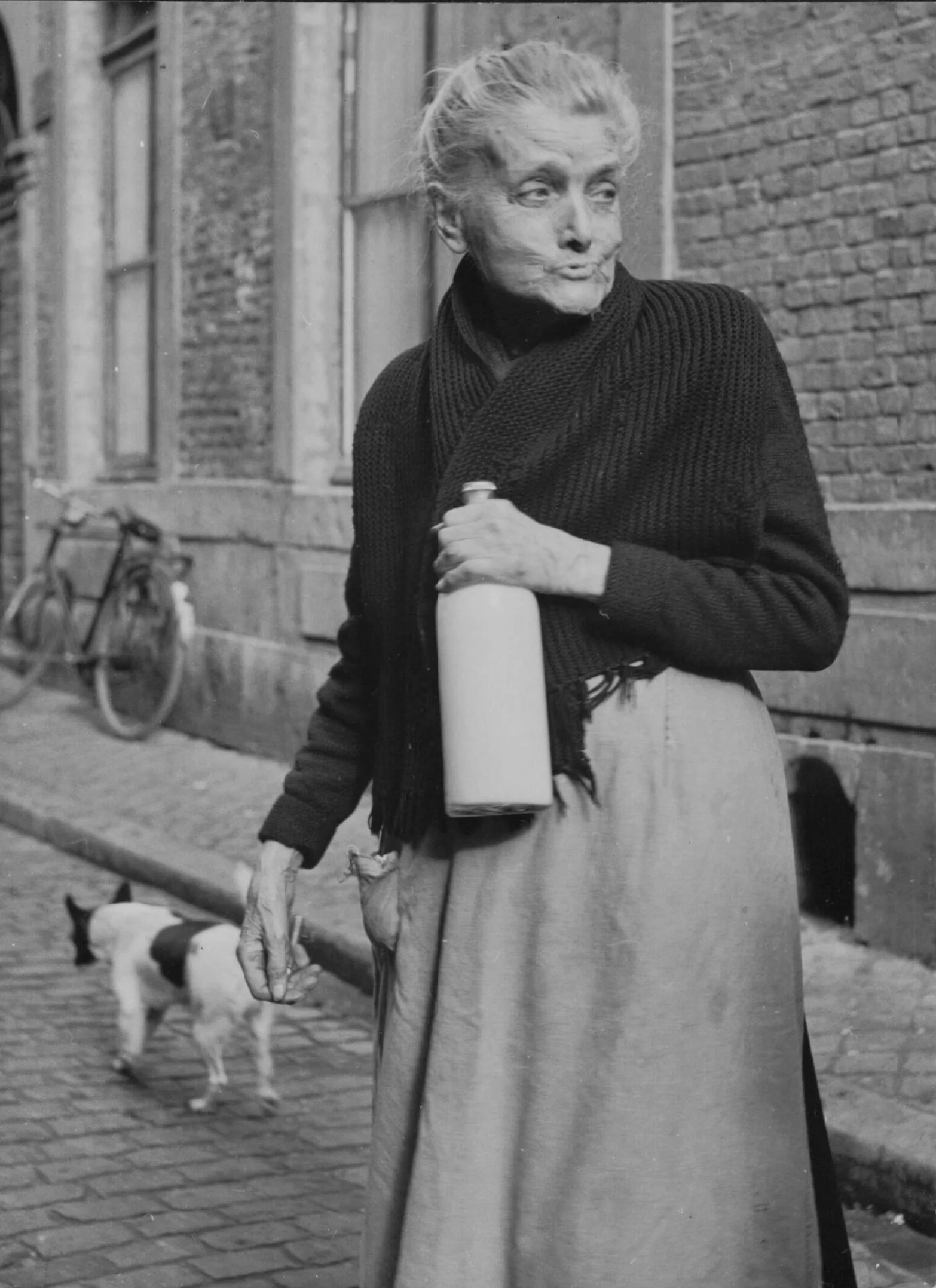 Vrouw in de Stokstraat heeft net melk gehaald, ca. 1954 [NA]