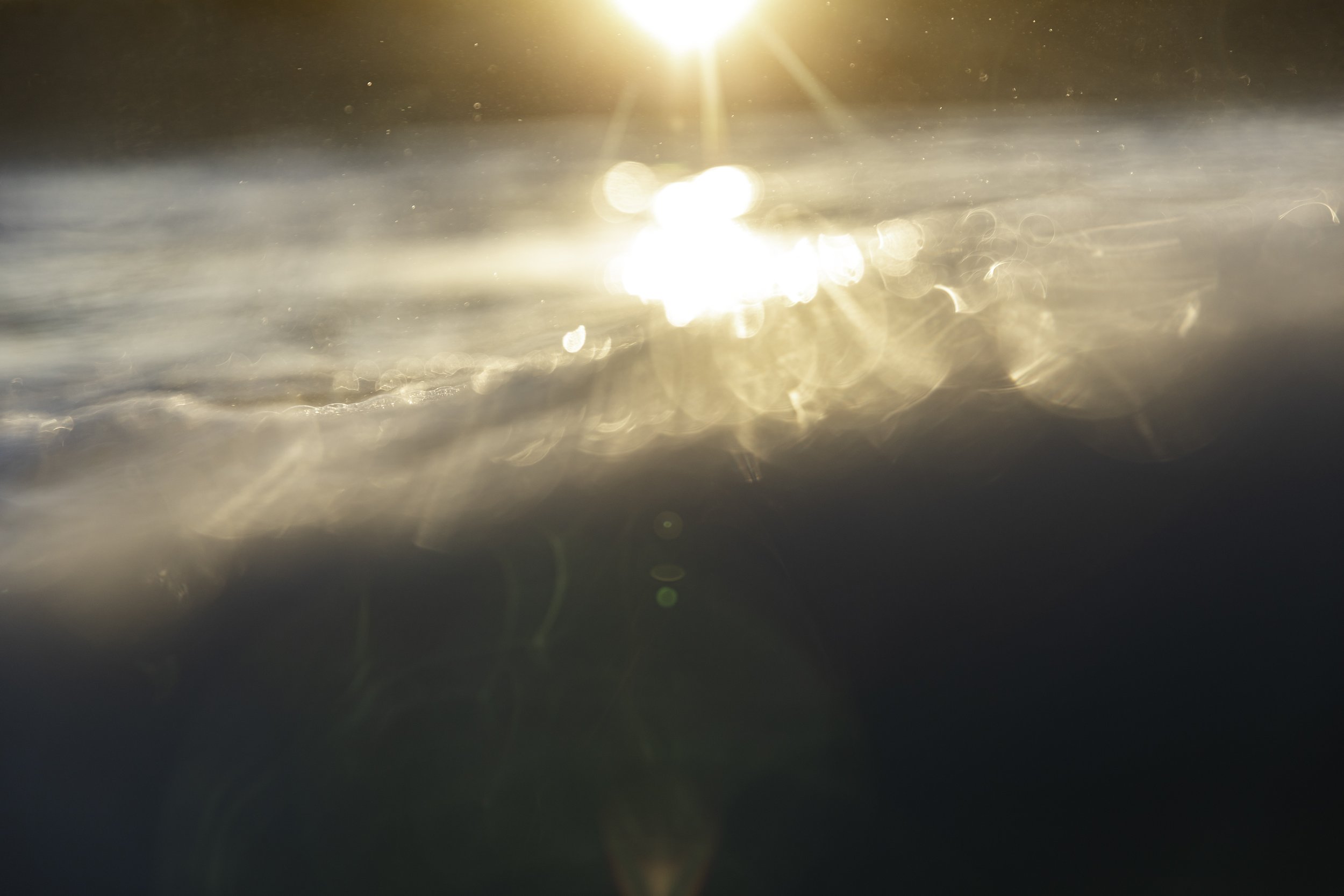 Sunlight reflecting off a calm body of water creating bright glare and glare spots.