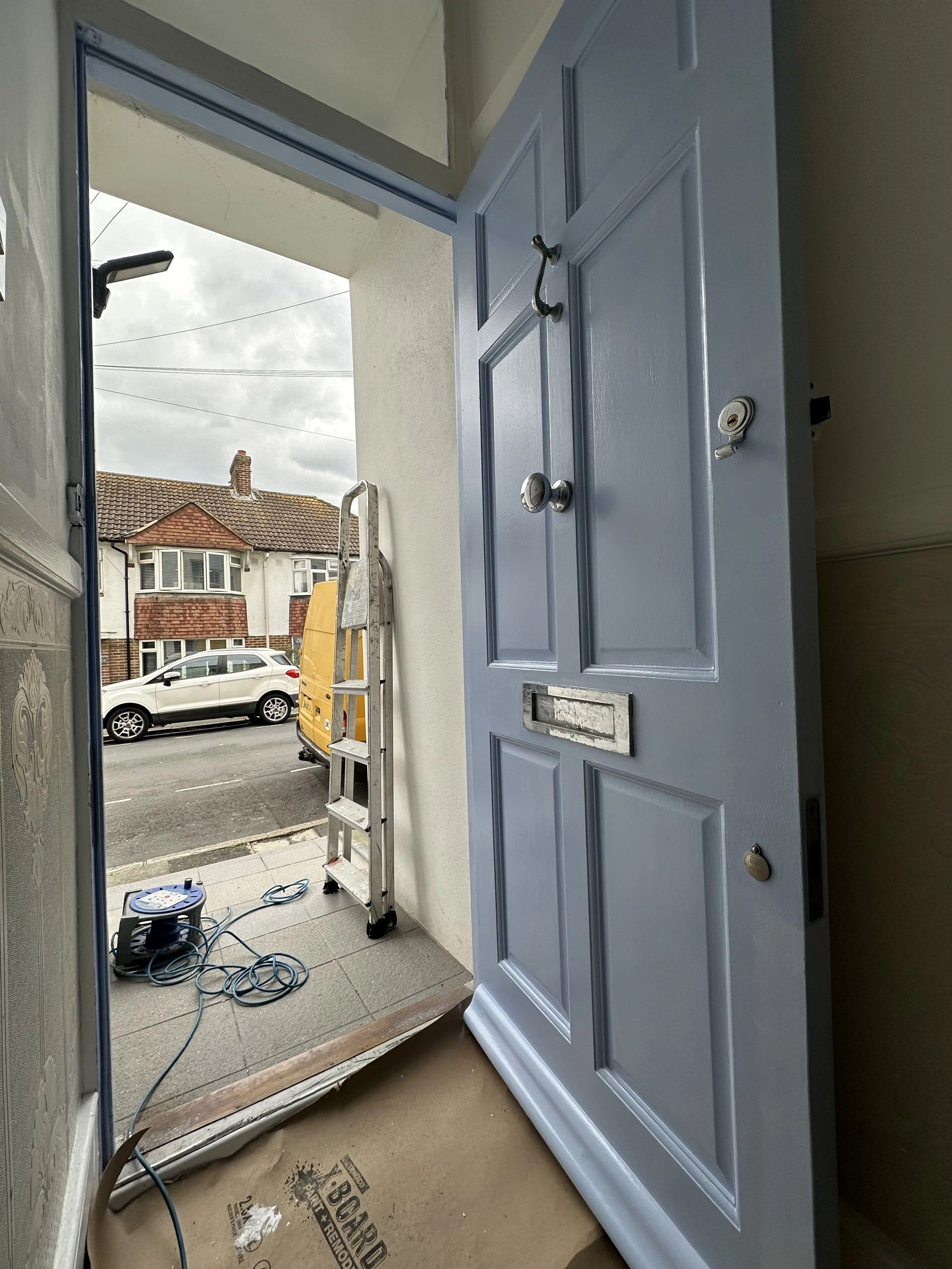 A front door painted in Zinsser All-Coat Oil, Satin finish. The light blue was chosen to mirror the sea visible at the end of the street. 
