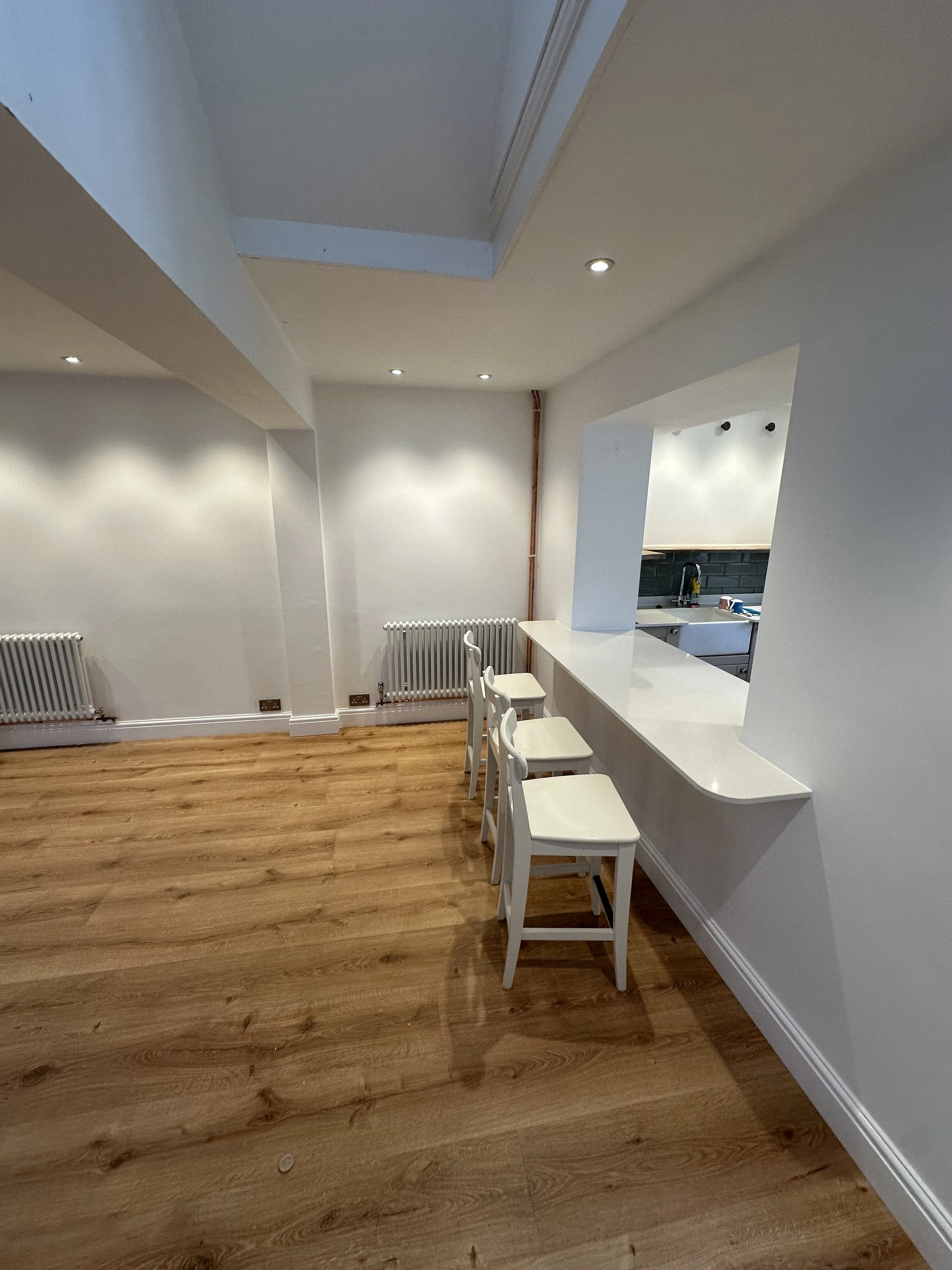 Basement renovation with ceilings and woodwork in brilliant white for a landlord's HMO. Features a service counter kitchen hatch. 