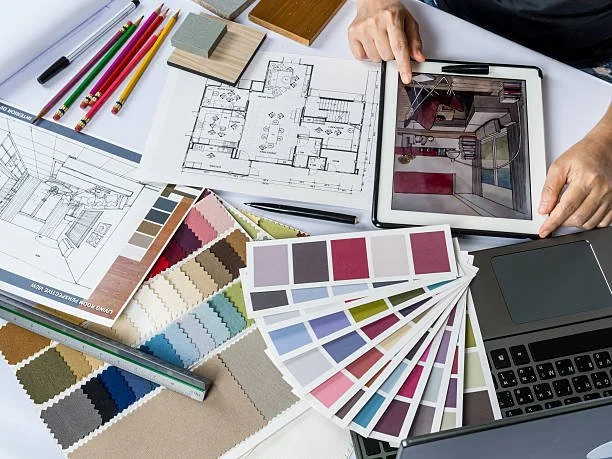 Architectural design workspace with floor plans, color swatches, digital tablet, and laptop.