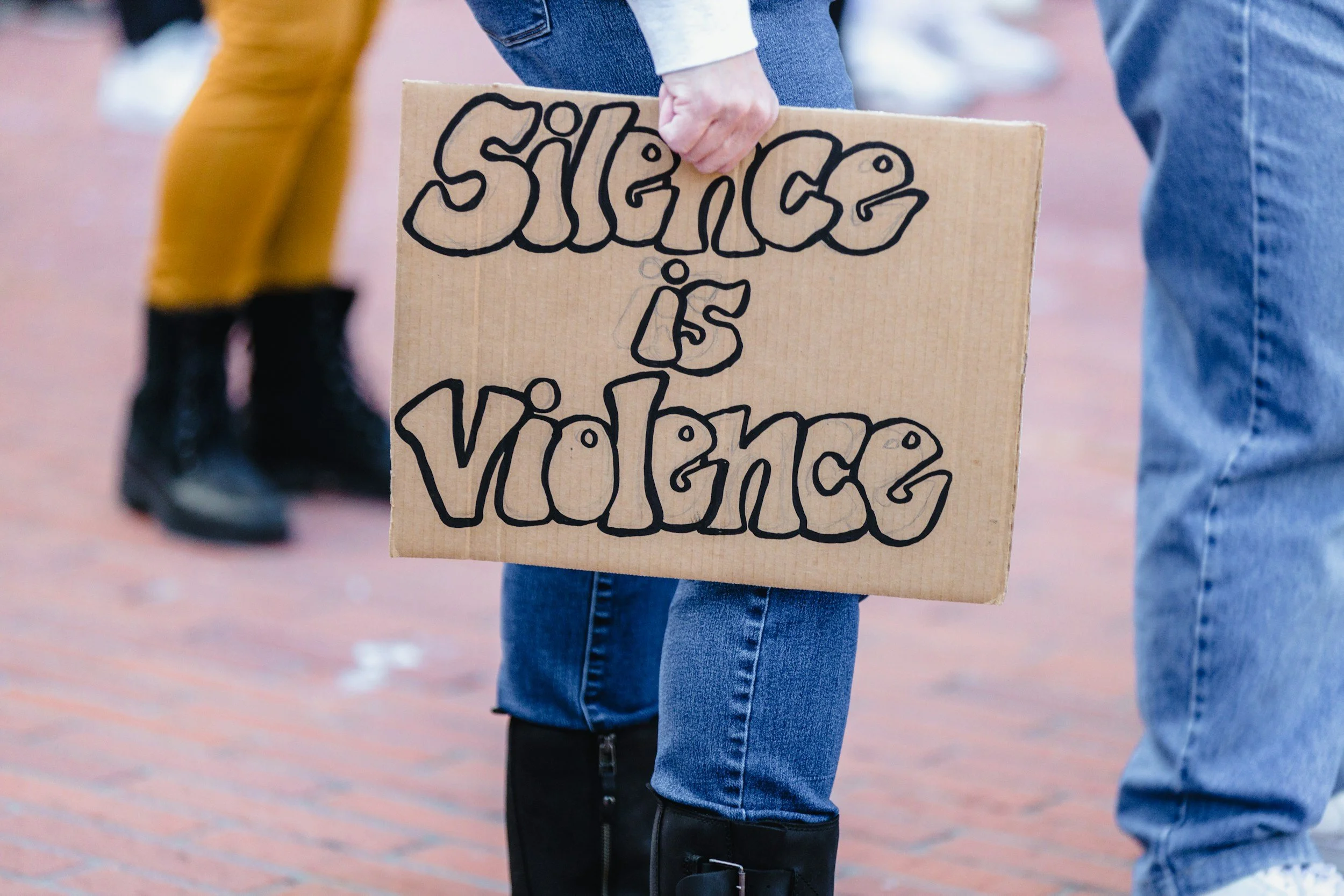 Eine Person hält ein Plakat mit der Aufschrift "Silence is Violence"