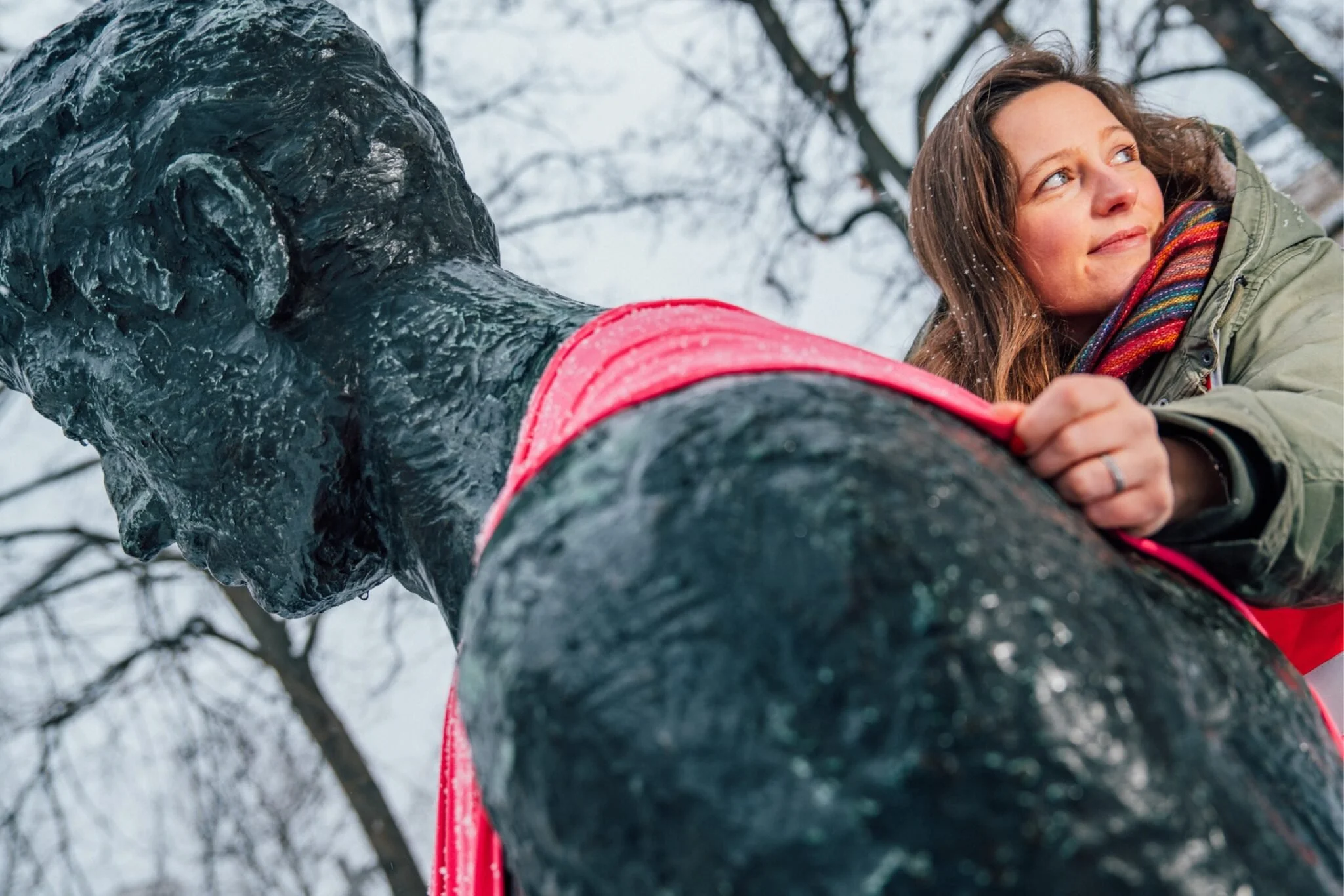 Tina Lüderitz klettert auf eine Bronze-Statue in Leipzig, um ein Baby-Tragetuch anzubringen.