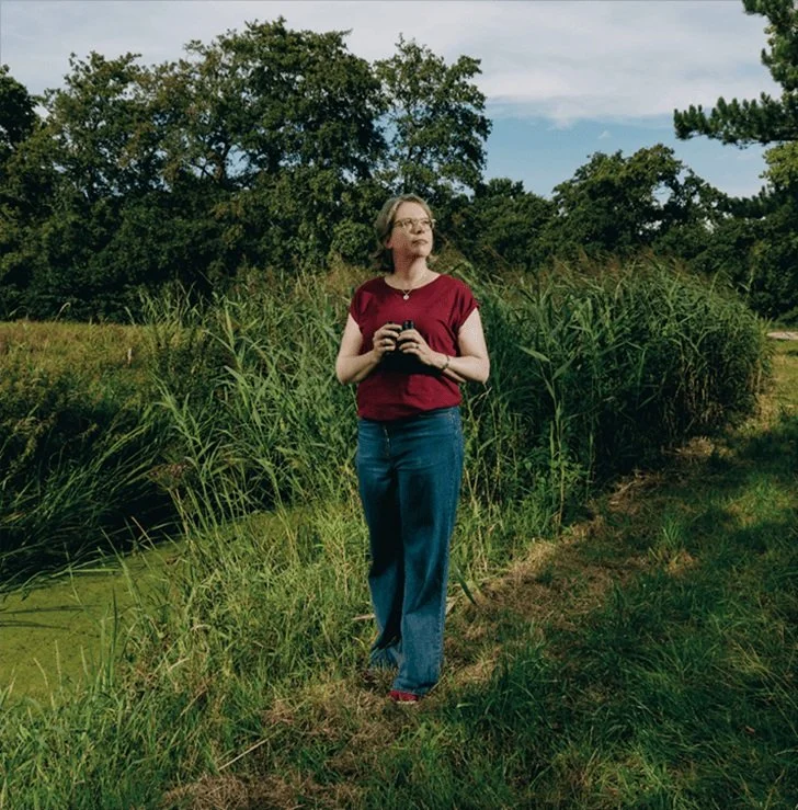 Die Ornithologin Silke Hartmann steht mit Fernglas in der Natur.