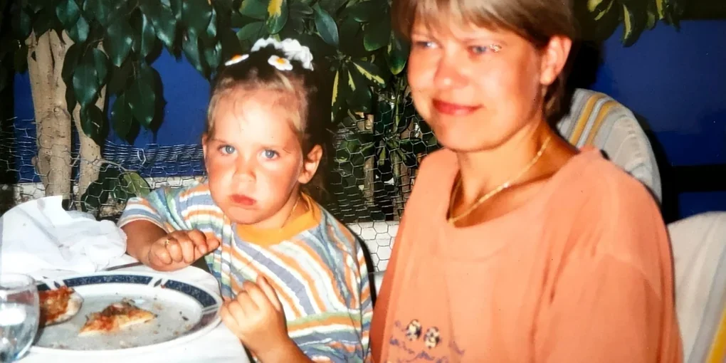 Die Autorin sitzt als Kind mit ihrer Mutter im Urlaub am Tisch.