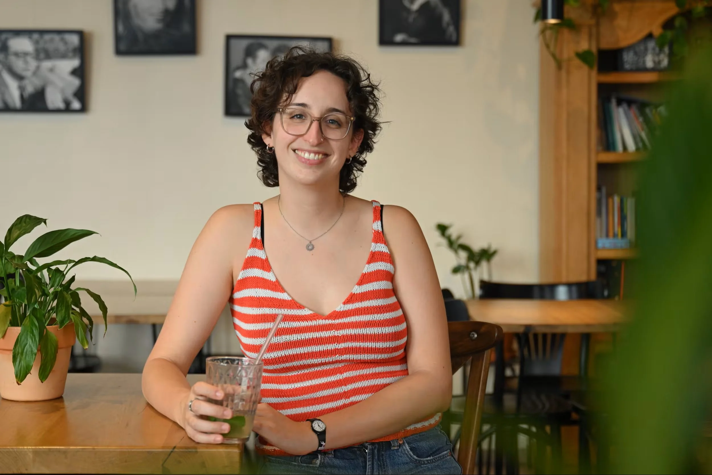 Eine junge Frau sitzt mit einer Limonade an einem Café-Tisch.