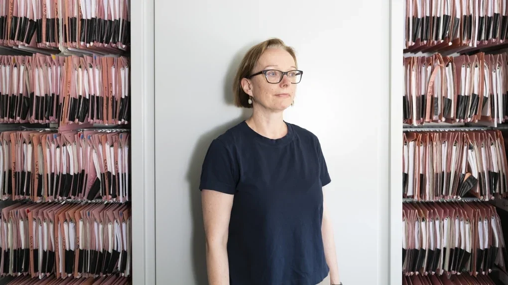 Eine Ärztin steht vor einem geöffneten Schrank mit Patient*innenakten