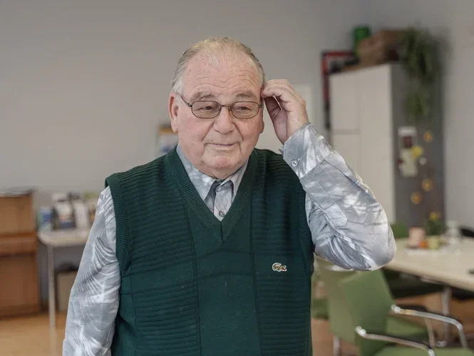 Ein alter Mann mit Pollunder und Brille blickt hoffnungsvoll in die Zukunft. 