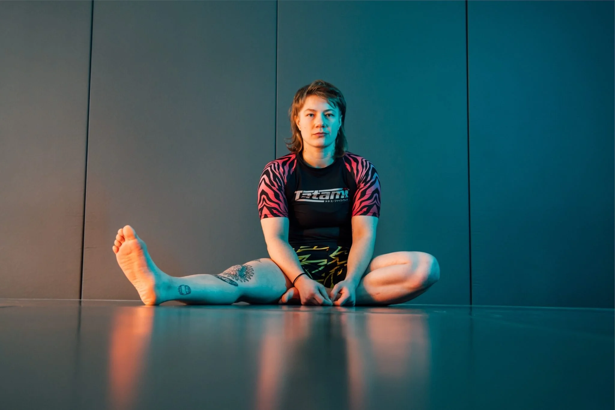 Anna Schmidt sitzt in ihren Sportklamotten auf dem Boden ihres Trainingsstudios.