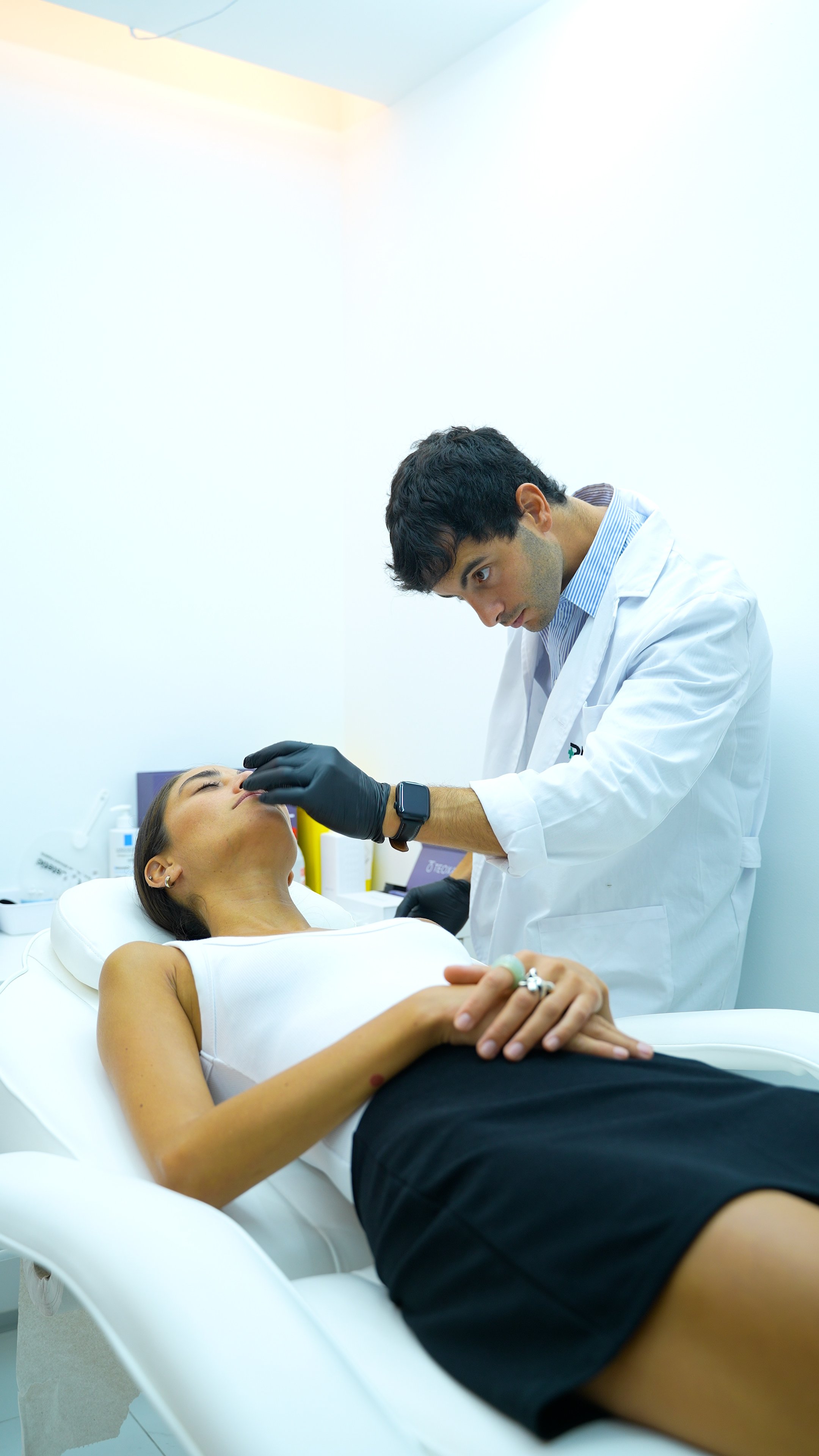 Famoso medico estetico, analizando rostro facial femenino para realiazar una armonización sin cirugia, en un consultorio blanco, limpio y elegante.