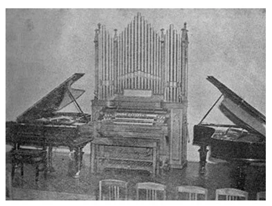 Palco do salão onde eram realizados concertos, com um órgão central e dois pianos ao lado 