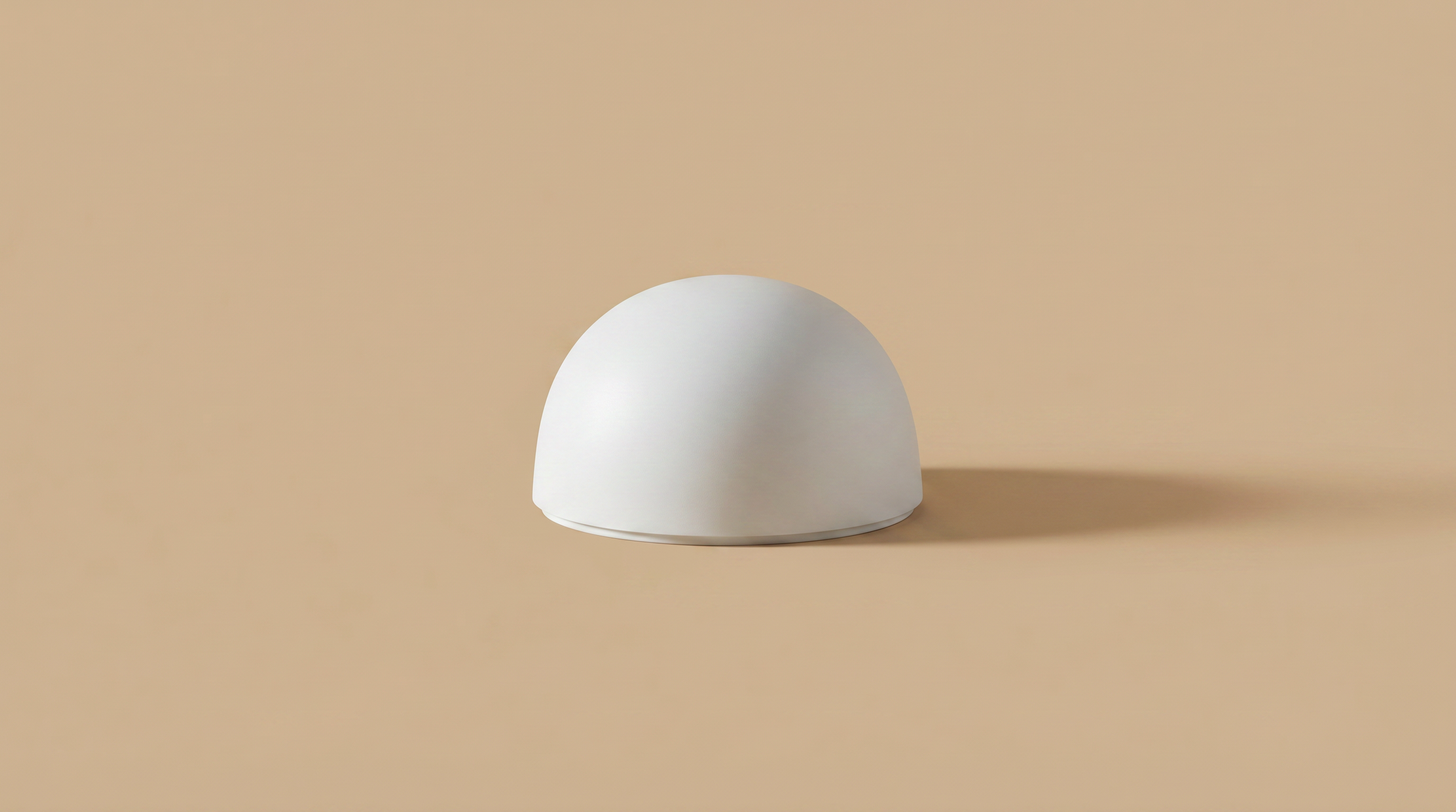 White, dome-shaped object on a beige background with a shadow to the right.