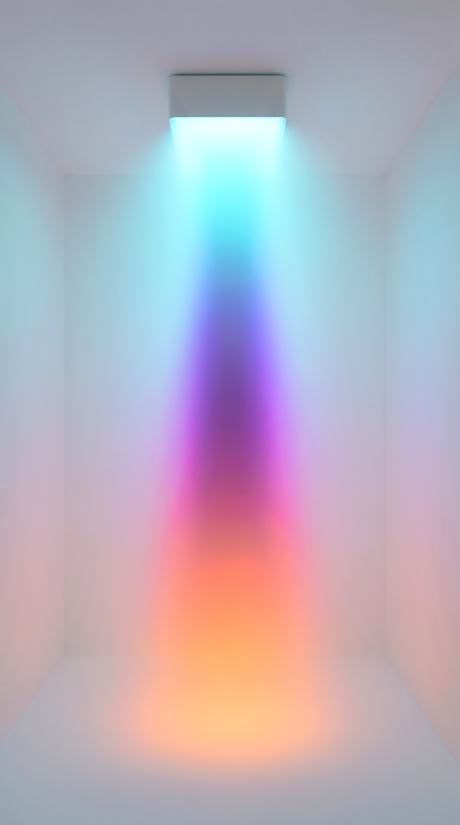 A room with a ceiling light that emits a colorful gradient, creating a multicolored glow on the white walls and floor.