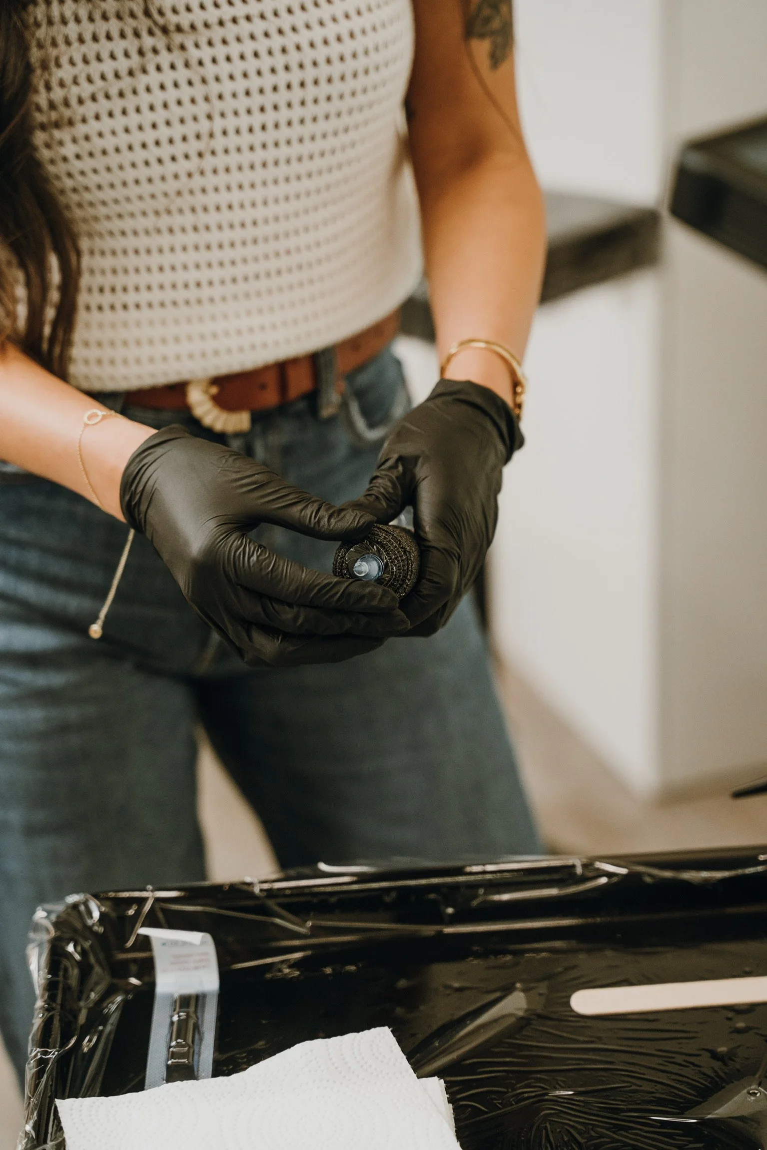 Person wearing black gloves holding a small object inside a small black case, with a white towel nearby.