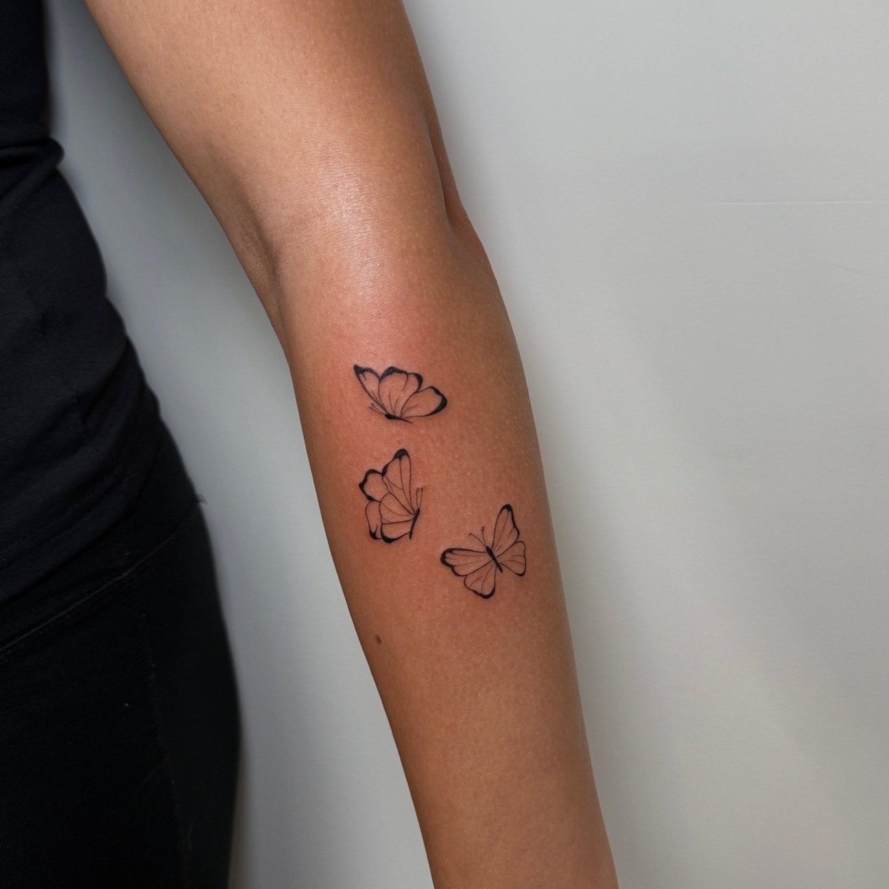 Tattoo of three butterflies on a person's forearm.