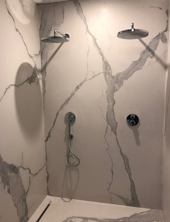 Inloopdouche met twee regendouches en een kiep draaien op een marmeren muur.