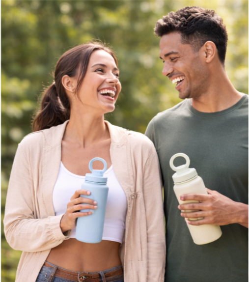 A smiling woman and man standing outdoors, each holding a reusable water bottle.