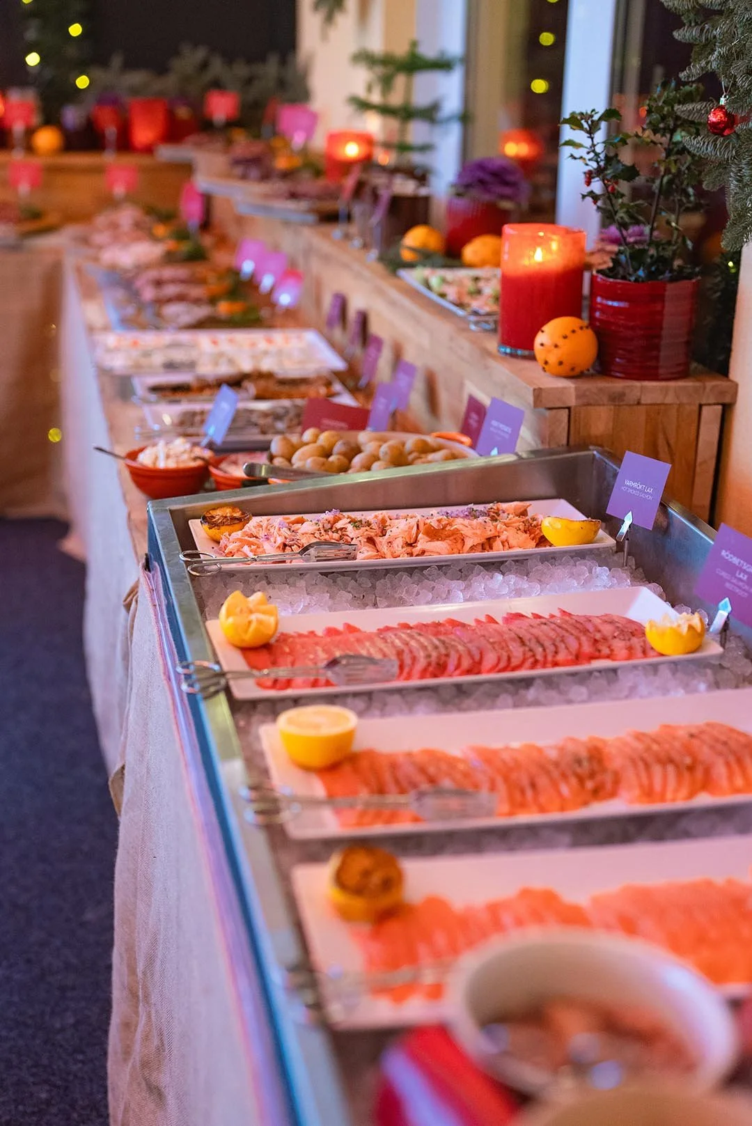 Julbord med julskinka, lax, sillar, köttbullar, lammull, och andra julrätter, dekorerat med ljus och julpynt.