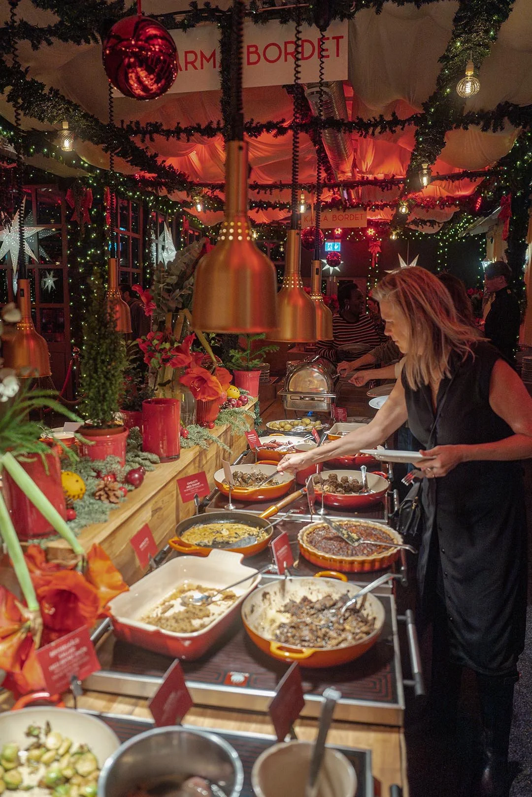 Juldekorationer och matbuffé på ett julbord, ett svenskt julbord med julgranar, stjärnor och julkulor i dekorationen.